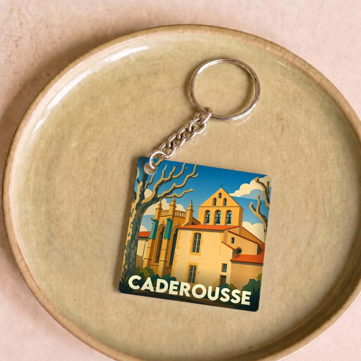Porte-clés souvenir de la ville de Caderousse avec une illustration stylisée d'une église provençale.