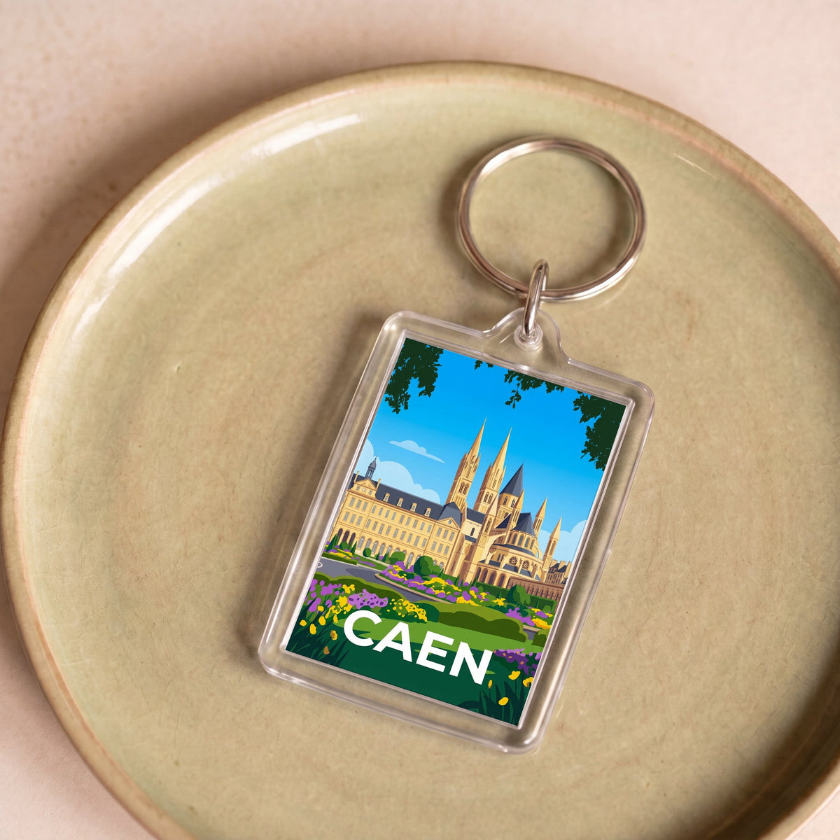 Porte-clés souvenir de la ville de Caen avec une illustration stylisée.