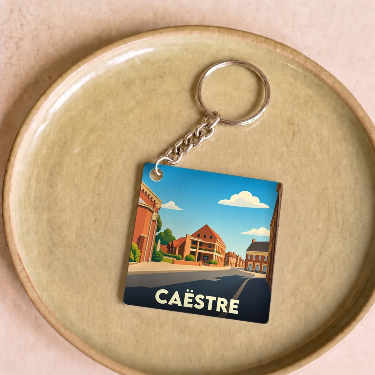 Porte-clés souvenir de la ville de Caëstre avec une illustration stylisée.