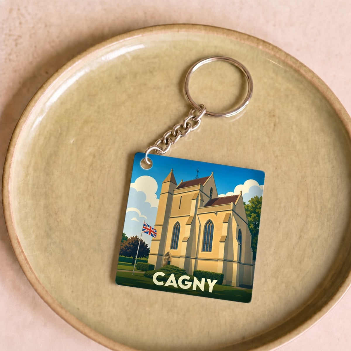 Porte-clés souvenir de la ville de Cagny avec une illustration stylisée d'une église sous un ciel bleu.