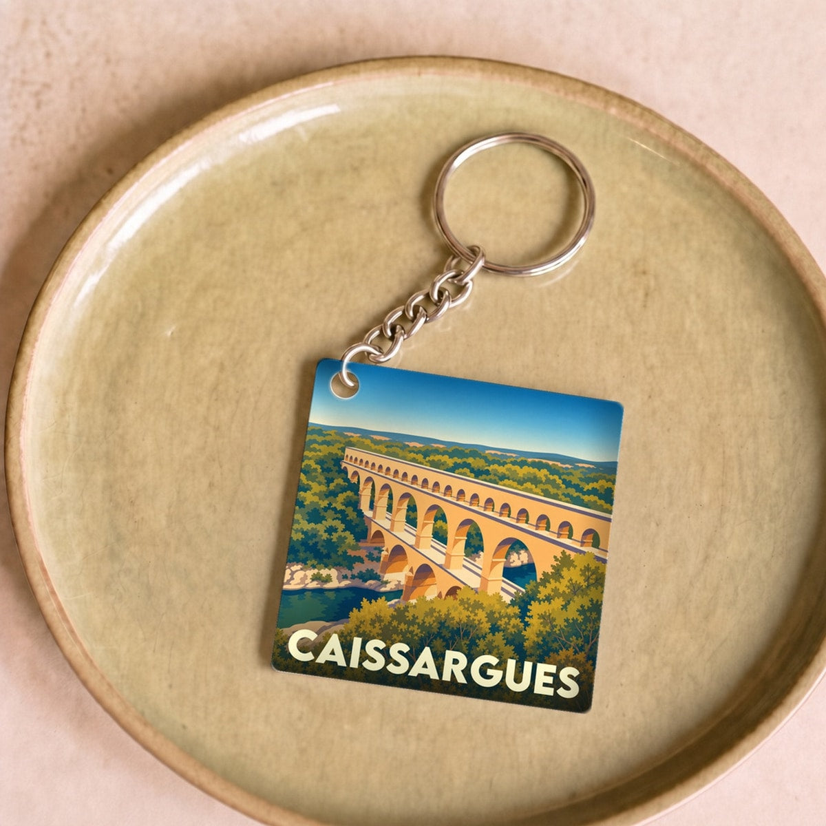 Porte-clés souvenir de la ville de Caissargues avec une illustration stylisée du Pont du Gard.