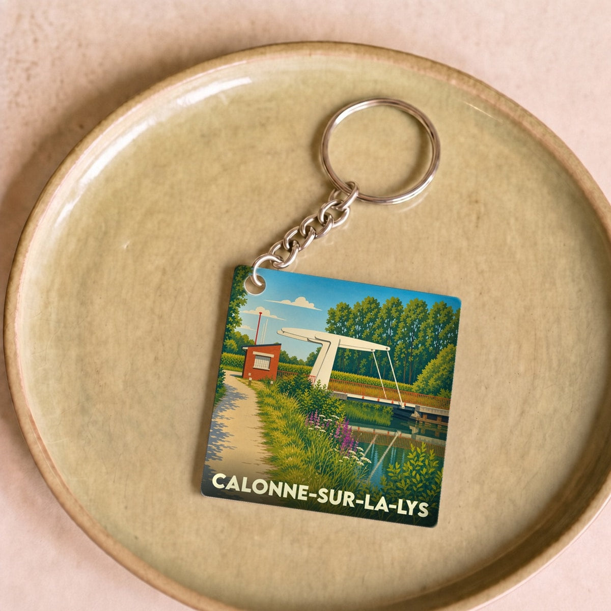 Porte-clés souvenir de la ville de Calonne-sur-la-Lys avec une illustration stylisée d'un pont levant au-dessus de l'eau.