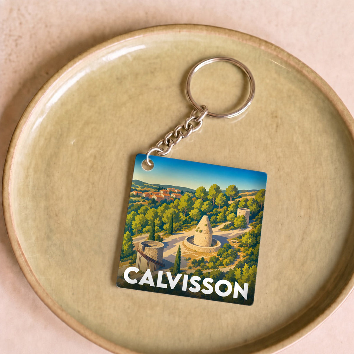 Porte-clés souvenir de la ville de Calvisson avec une illustration stylisée de son paysage et de ses moulins.