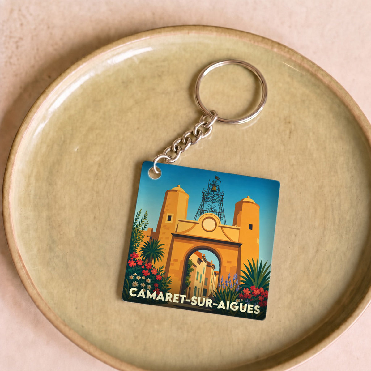Porte-clés souvenir de la ville de Camaret-sur-Aigues avec une illustration stylisée de sa porte fortifiée.