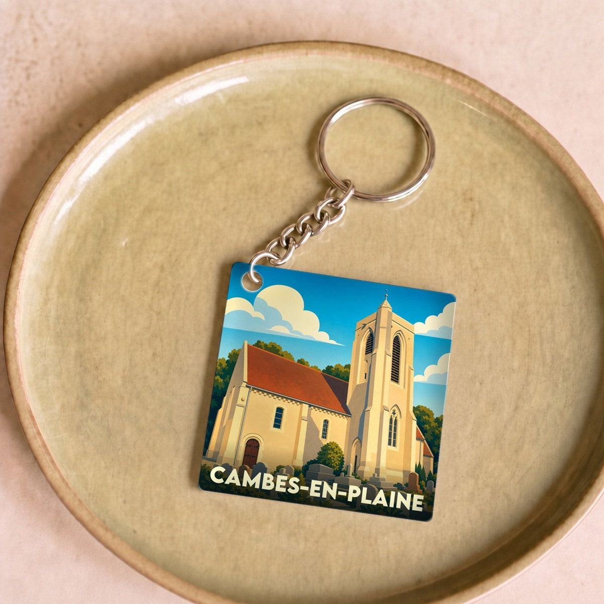 Porte-clés souvenir de la ville de Cambes-en-Plaine avec une illustration stylisée de son église.