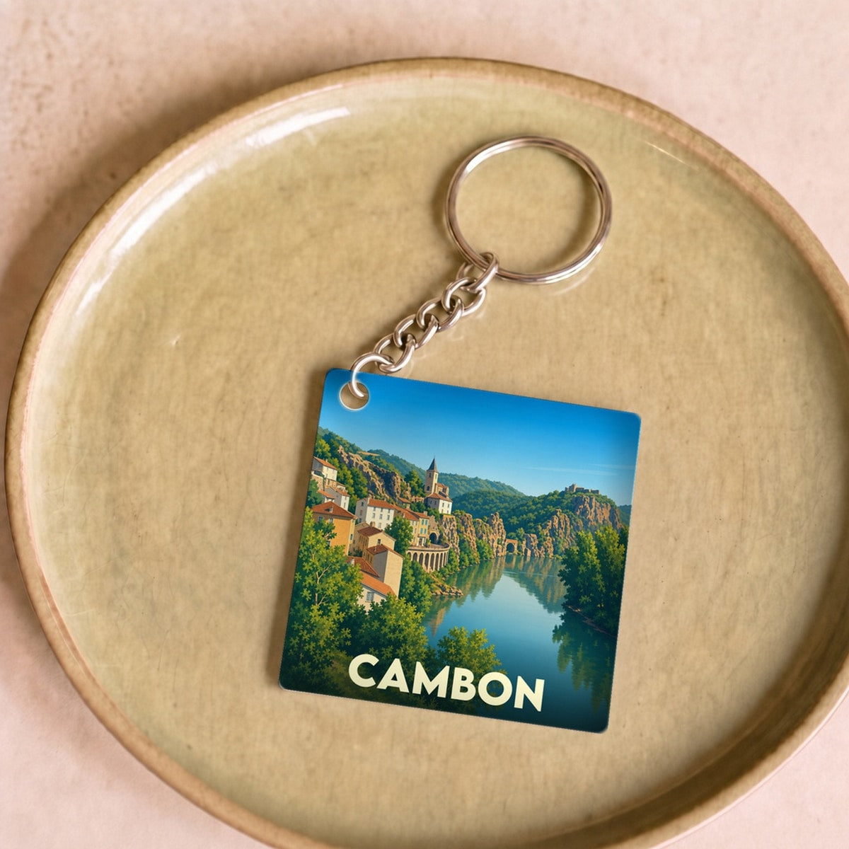 Porte-clés souvenir de la ville de Cambon avec une illustration stylisée d'un paysage fluvial.