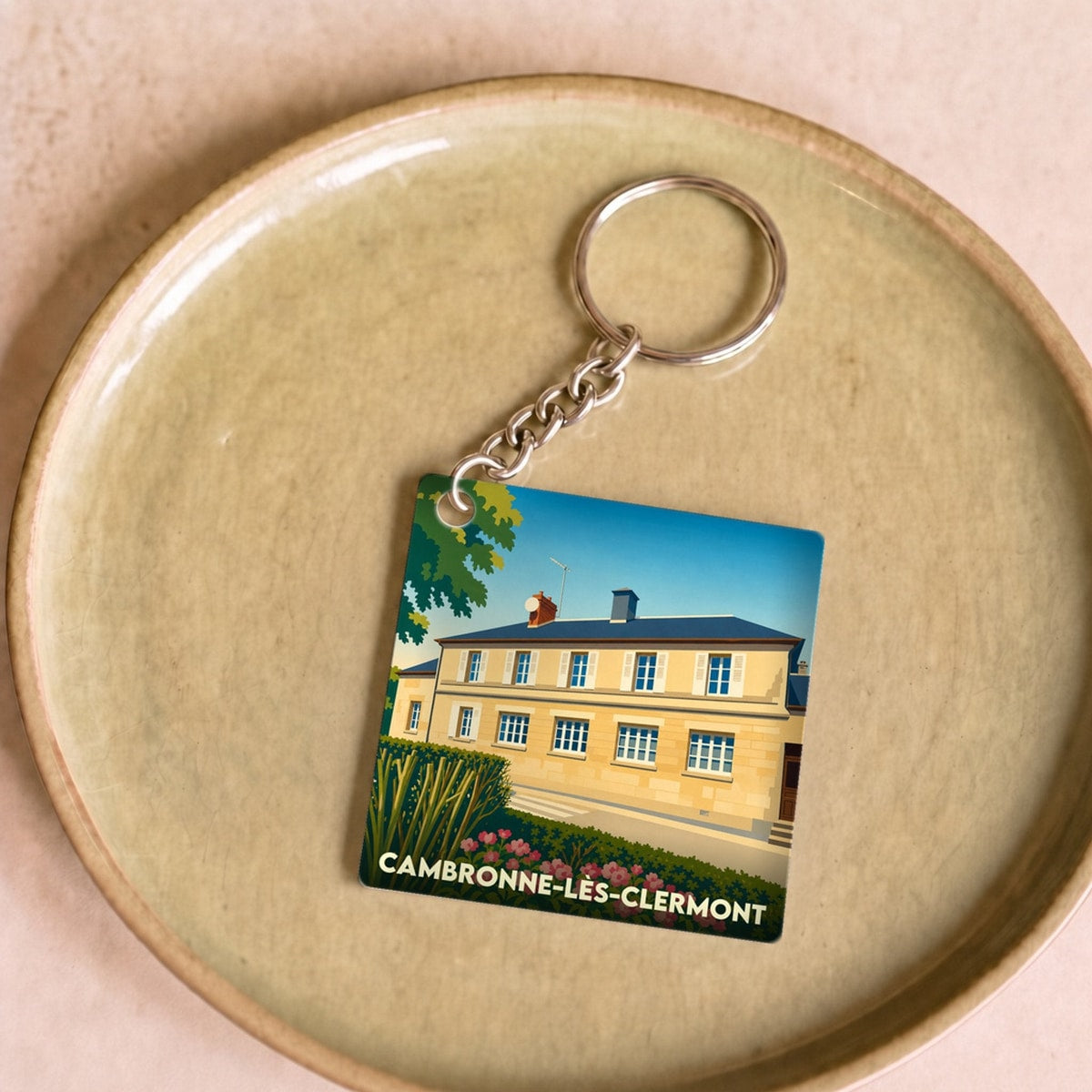 Porte-clés souvenir de la ville de Cambronne-lès-Clermont avec une illustration stylisée.