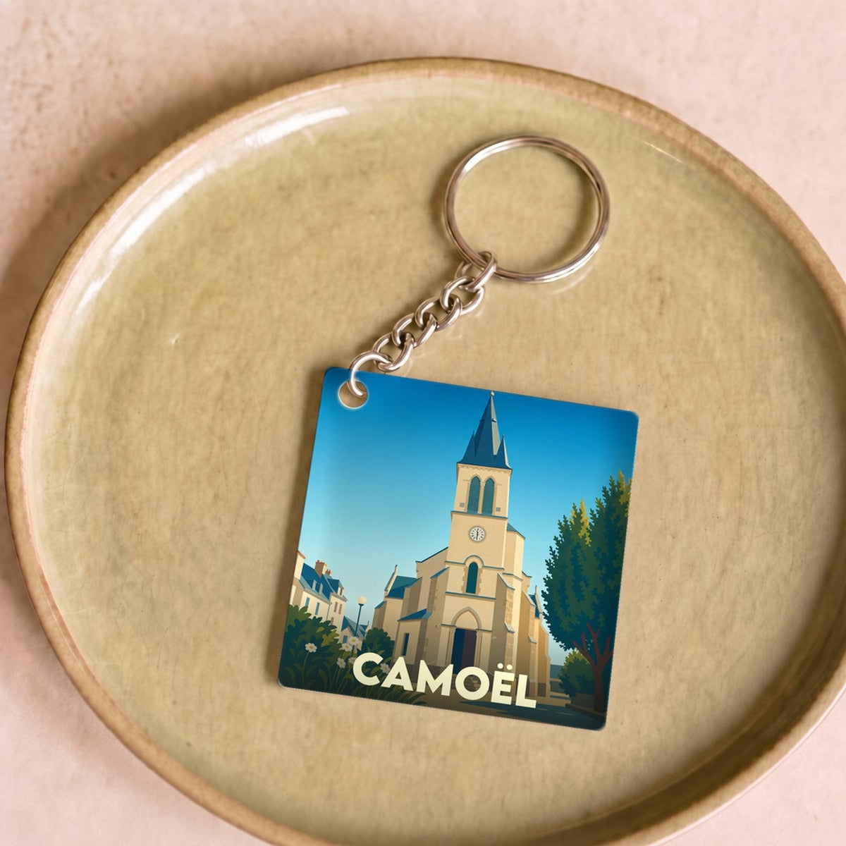 Porte-clés souvenir de la ville de Camoël avec une illustration stylisée de son église.