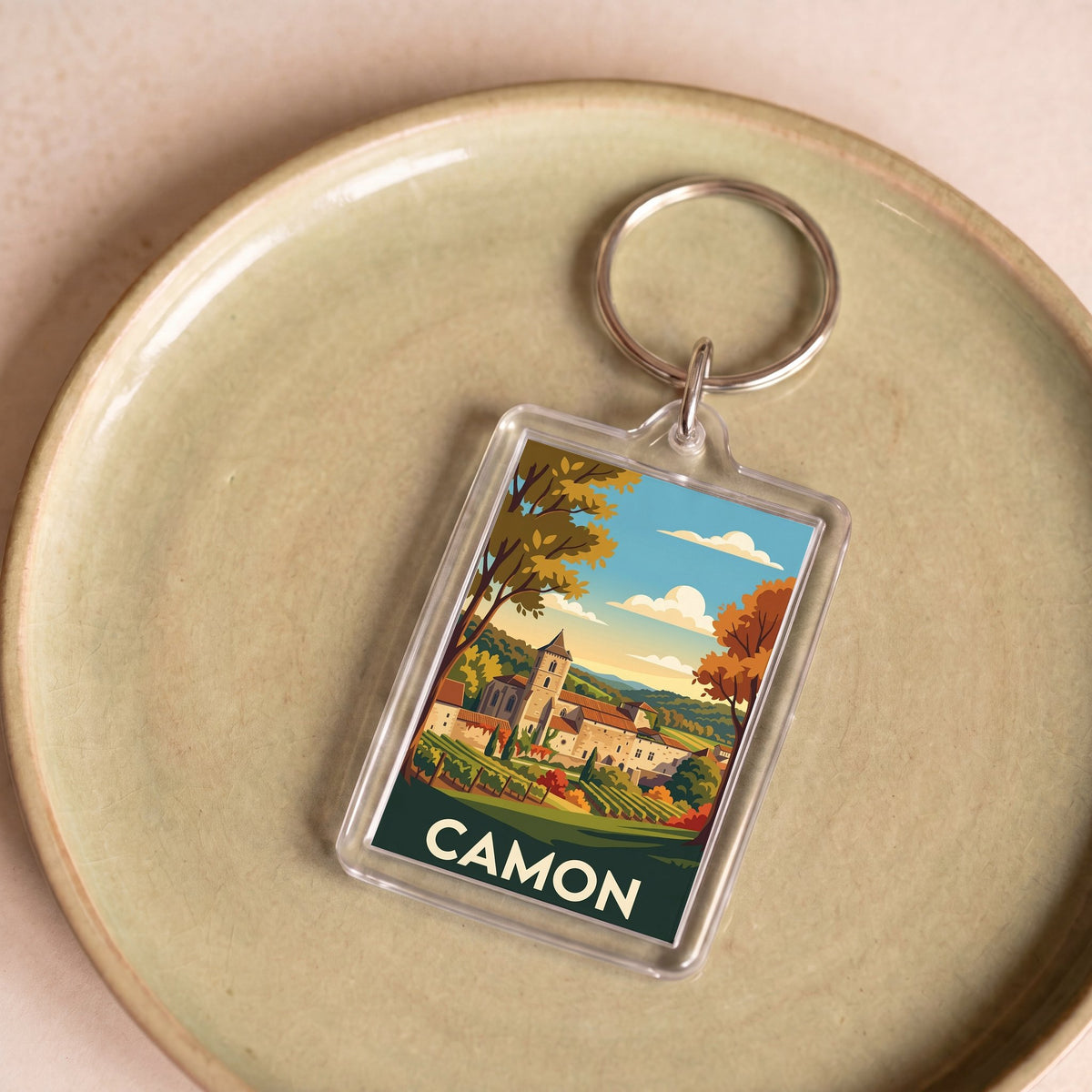 Porte-clés souvenir de la ville de Camon avec une illustration stylisée de son paysage.