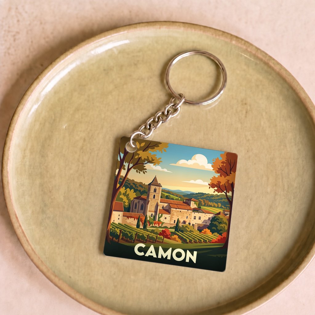 Porte-clés souvenir de la ville de Camon avec une illustration stylisée de son paysage.