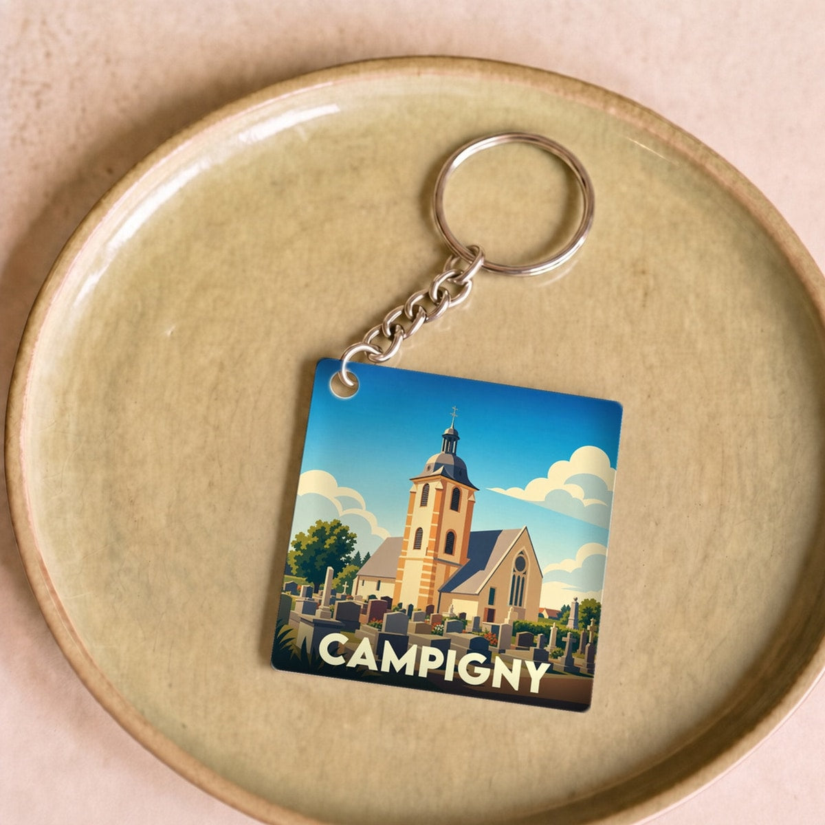 Porte-clés souvenir de la ville de Campigny avec une illustration stylisée d'une église et de son cimetière.