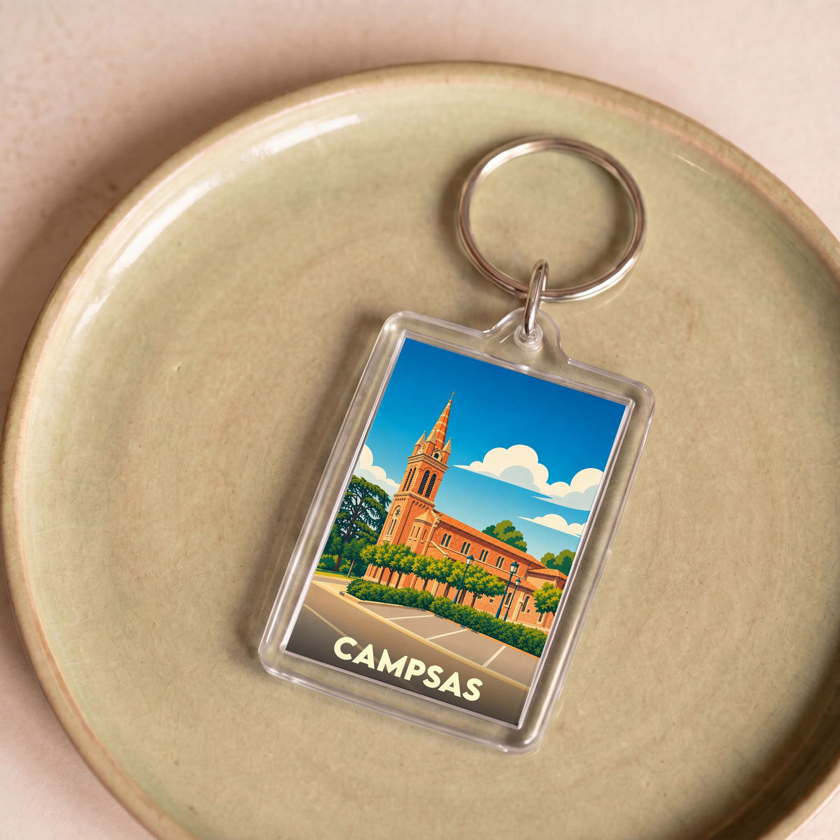 Porte-clés souvenir de la ville de Campsas avec une illustration stylisée de son église.