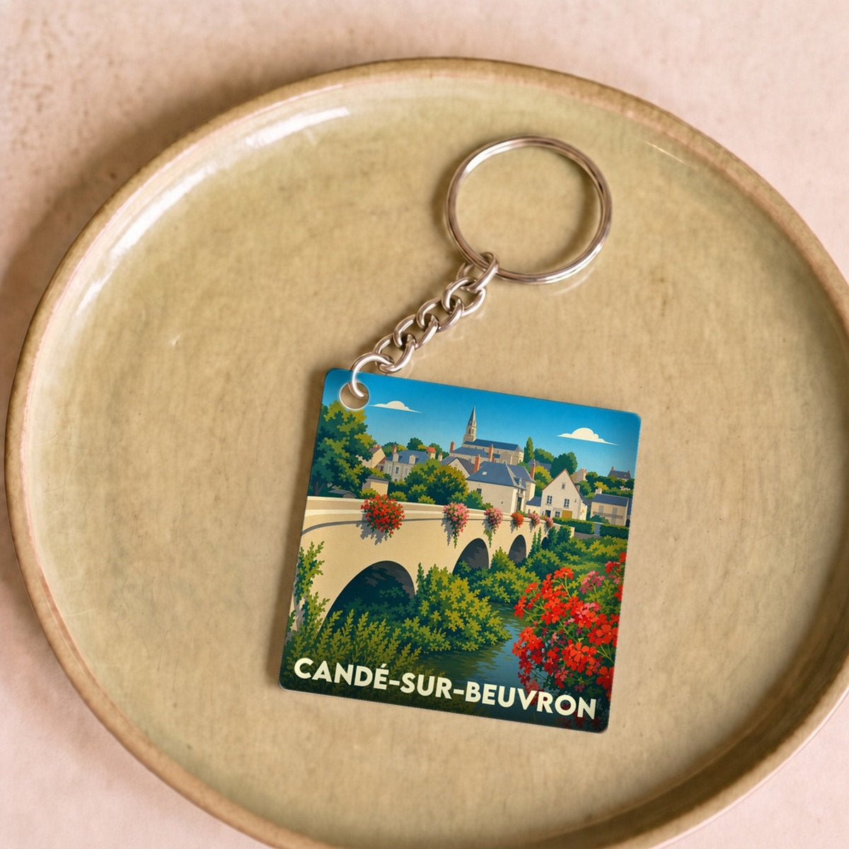 Porte-clés souvenir de la ville de Candé-sur-Beuvron avec une illustration stylisée de son pont fleuri.