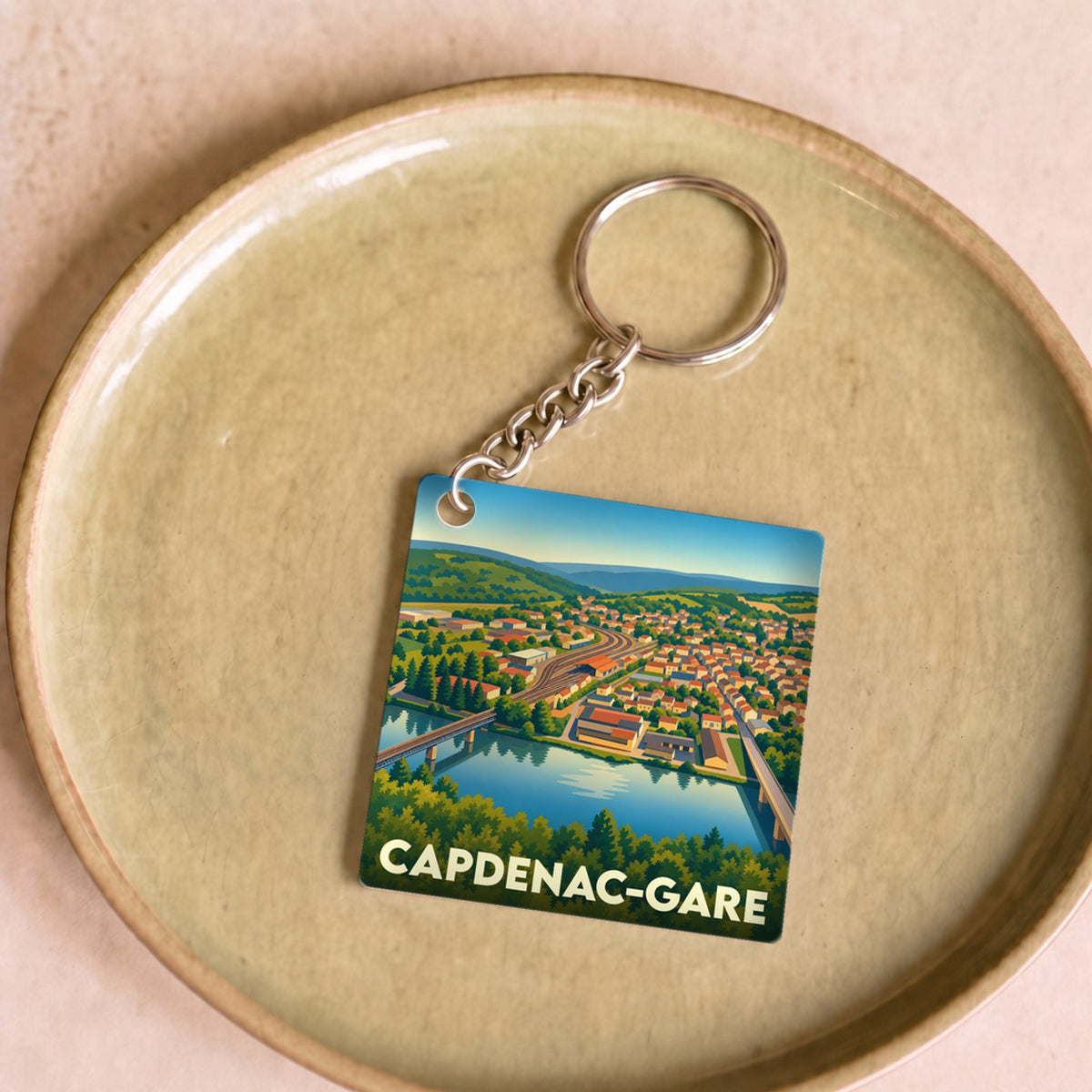 Porte-clés souvenir de Capdenac-Gare avec une illustration stylisée de la ville et de sa rivière.