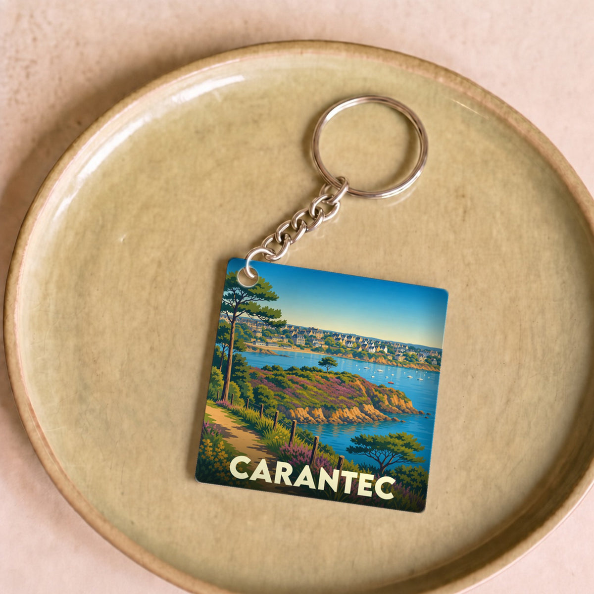 Porte-clés souvenir de la ville de Carantec avec une illustration stylisée d'un paysage côtier breton.