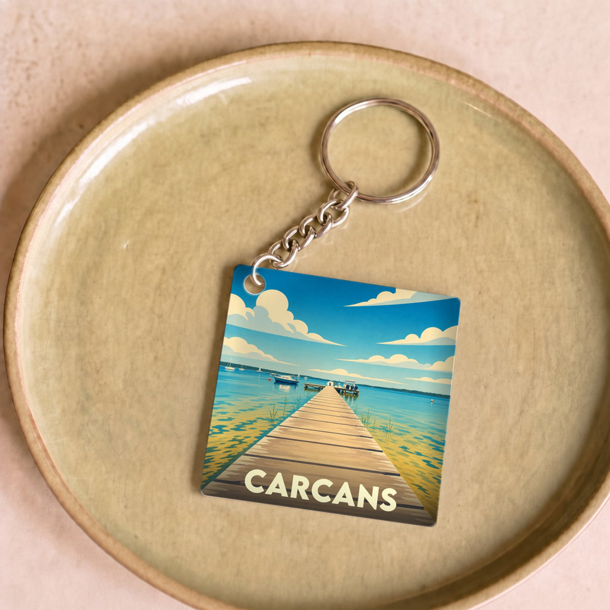 Porte-clés souvenir de la ville de Carcans avec une illustration stylisée d'un ponton sur le lac.