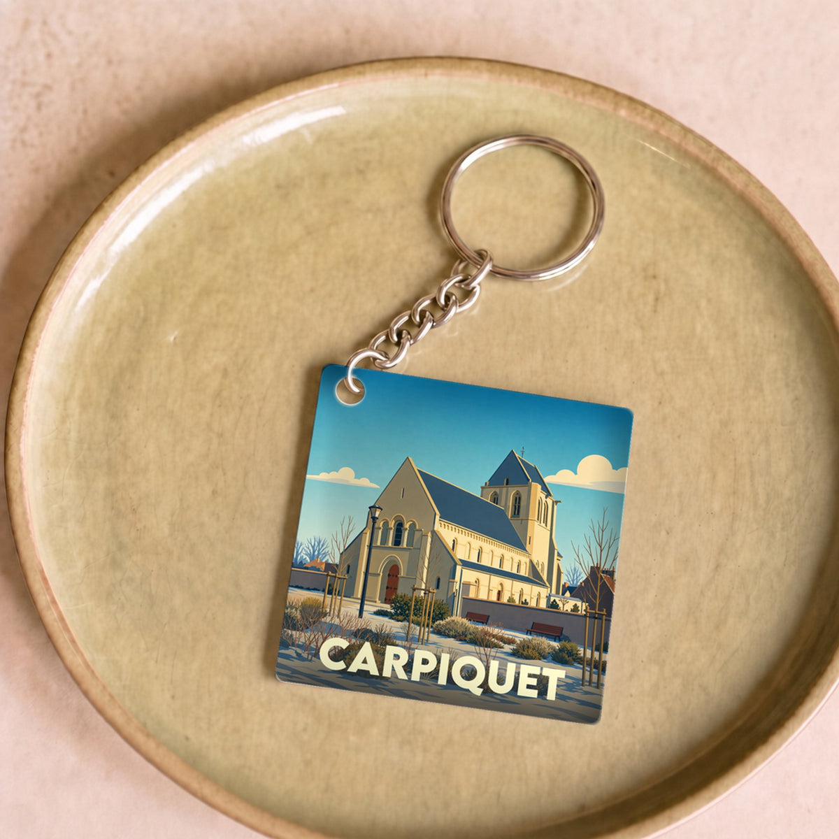Porte-clés souvenir de la ville de Carpiquet avec une illustration stylisée de son église.