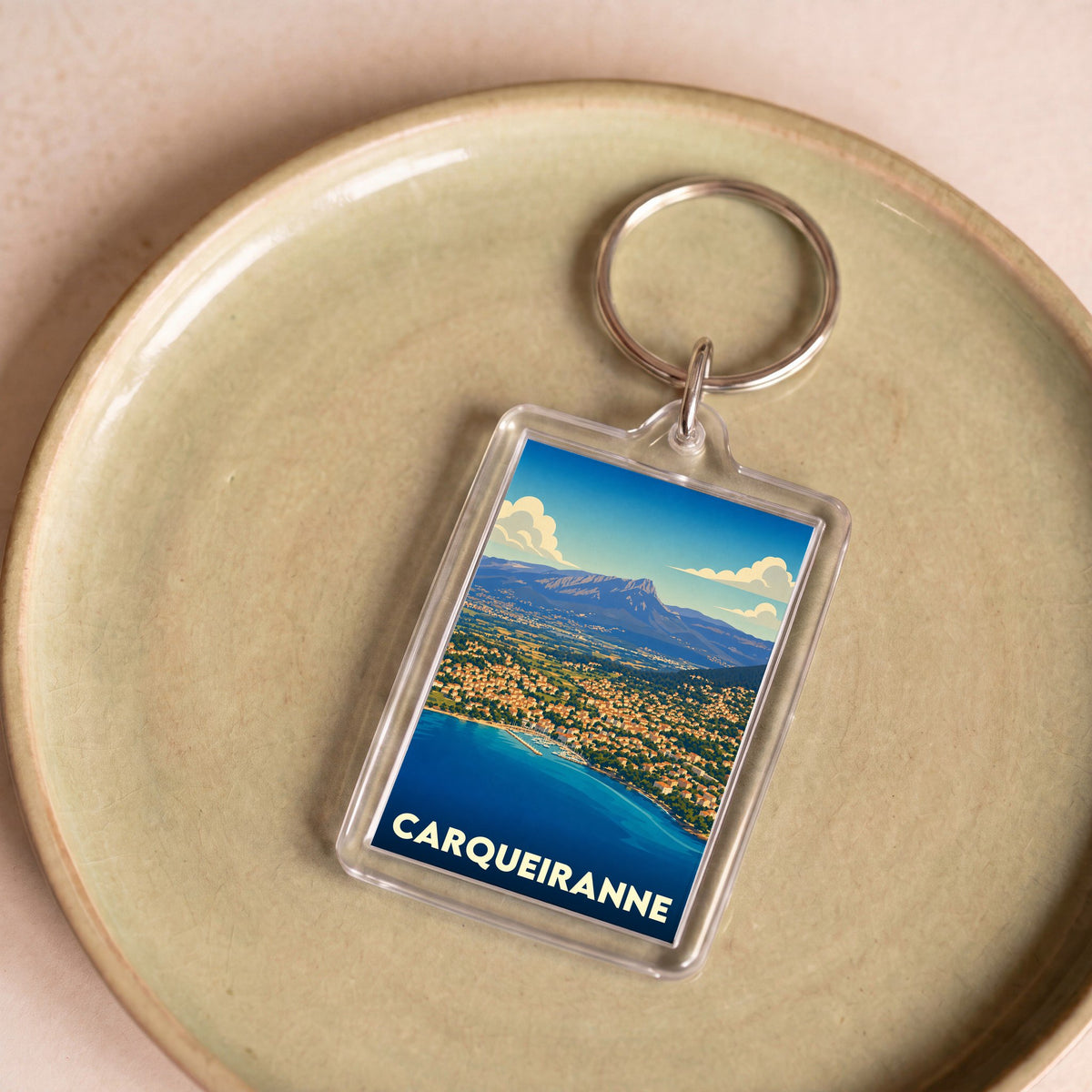 Porte-clés souvenir de la ville de Carqueiranne avec une illustration stylisée d'un paysage côtier.