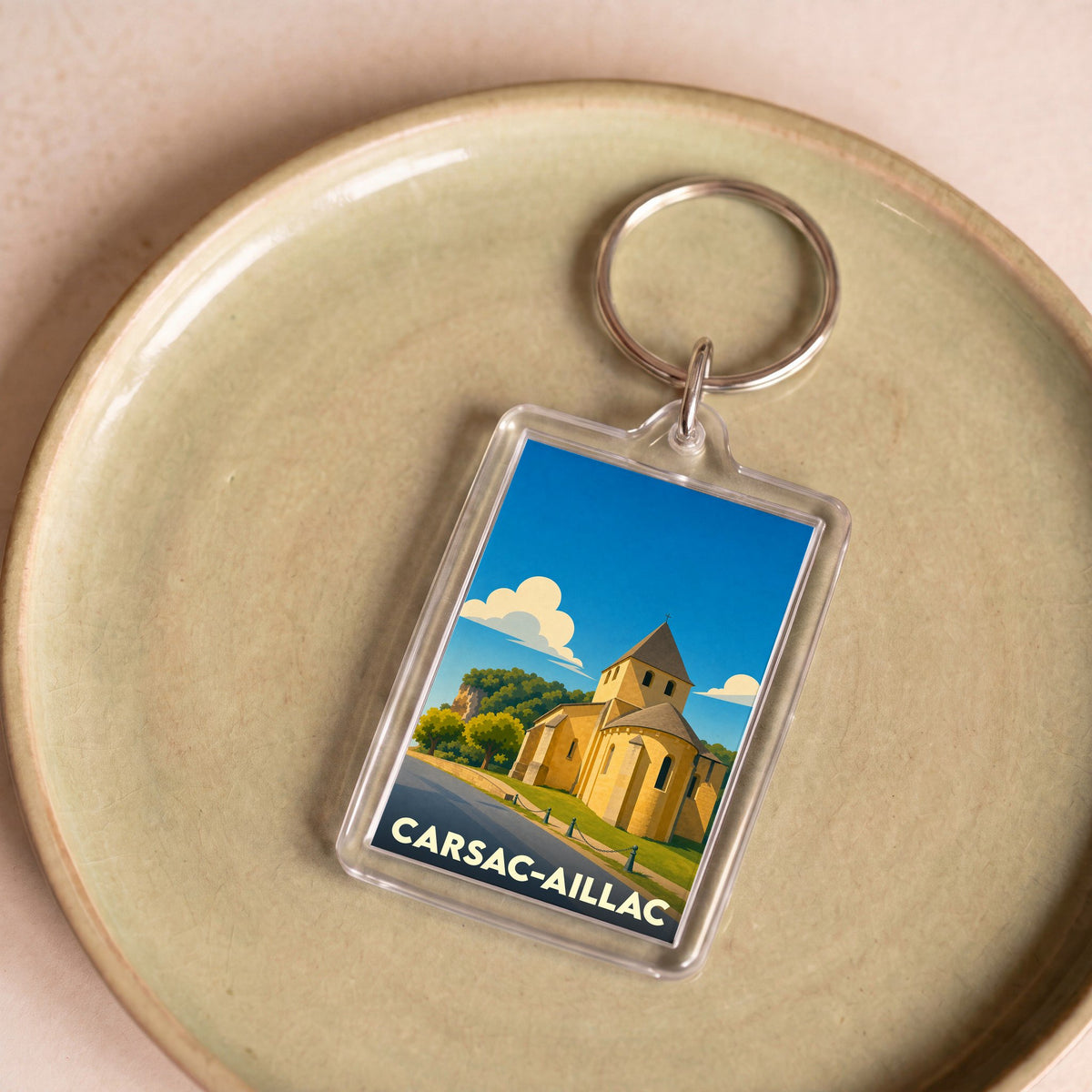 Porte-clés souvenir de la ville de Carsac-Aillac avec une illustration stylisée de son église romane.