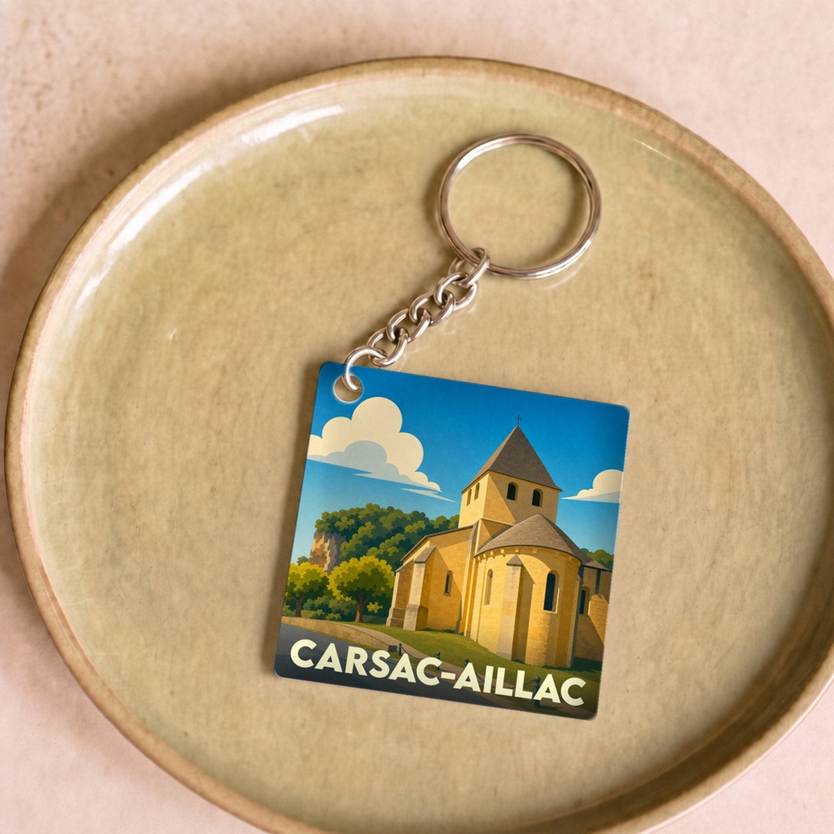 Porte-clés souvenir de la ville de Carsac-Aillac avec une illustration stylisée de son église romane.