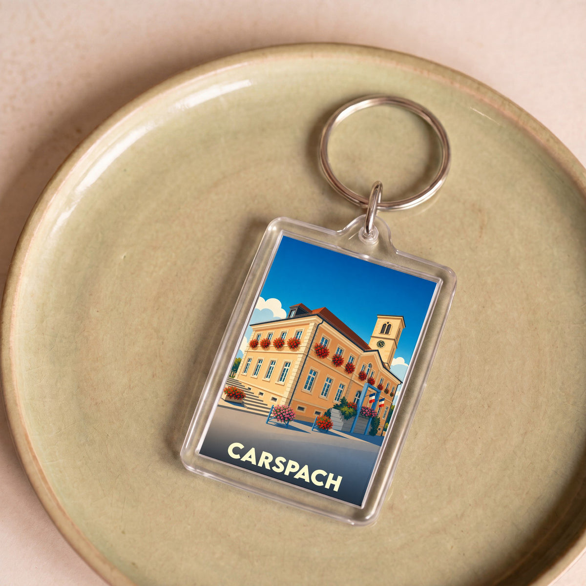 Porte-clés souvenir de la ville de Carspach avec une illustration stylisée de sa mairie.