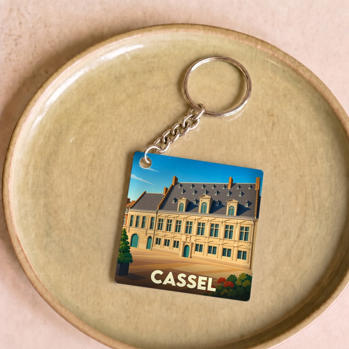 Porte-clés souvenir de la ville de Cassel avec une illustration stylisée d'un bâtiment historique.