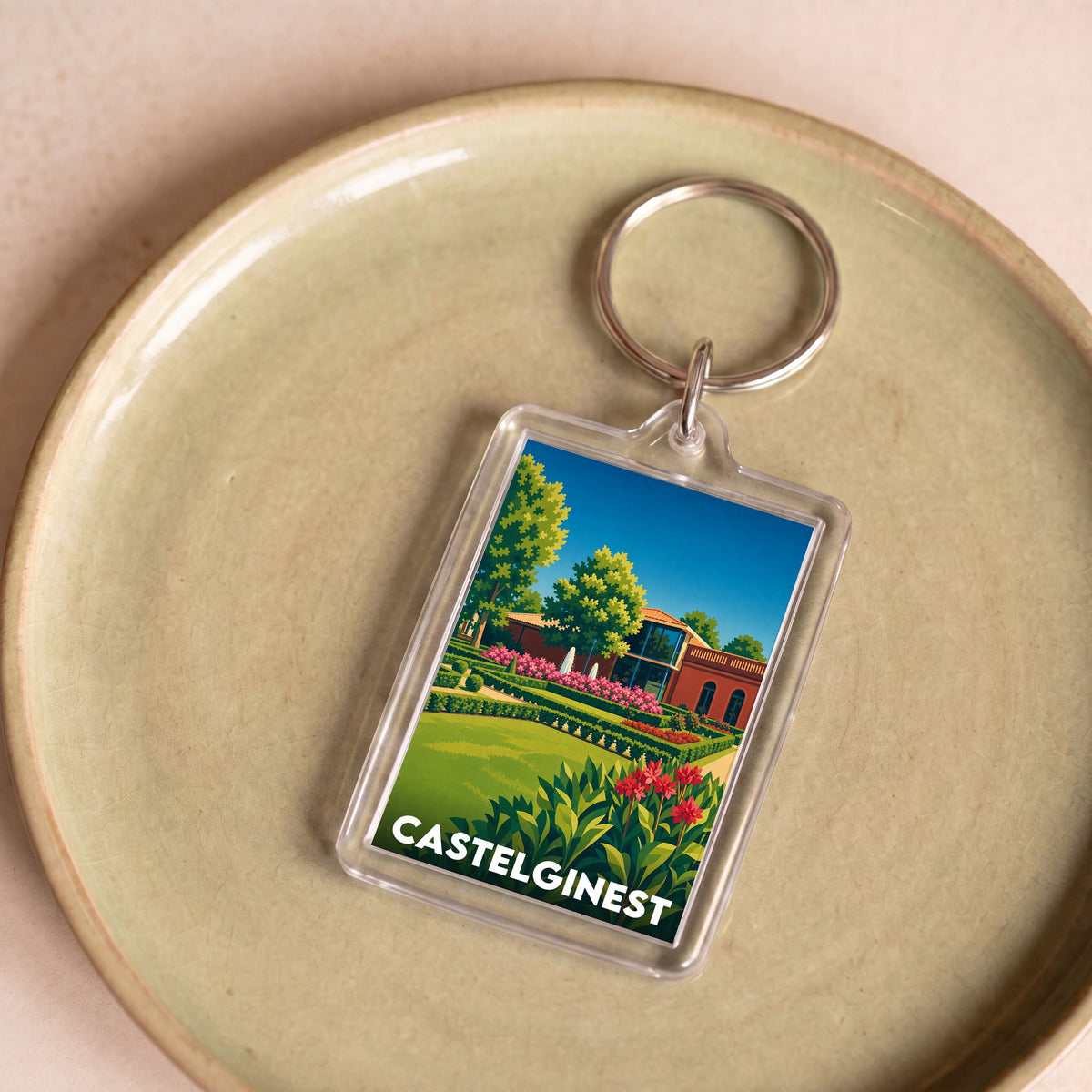 Porte-clés souvenir de la ville de Castelginest avec une illustration stylisée de ses jardins.