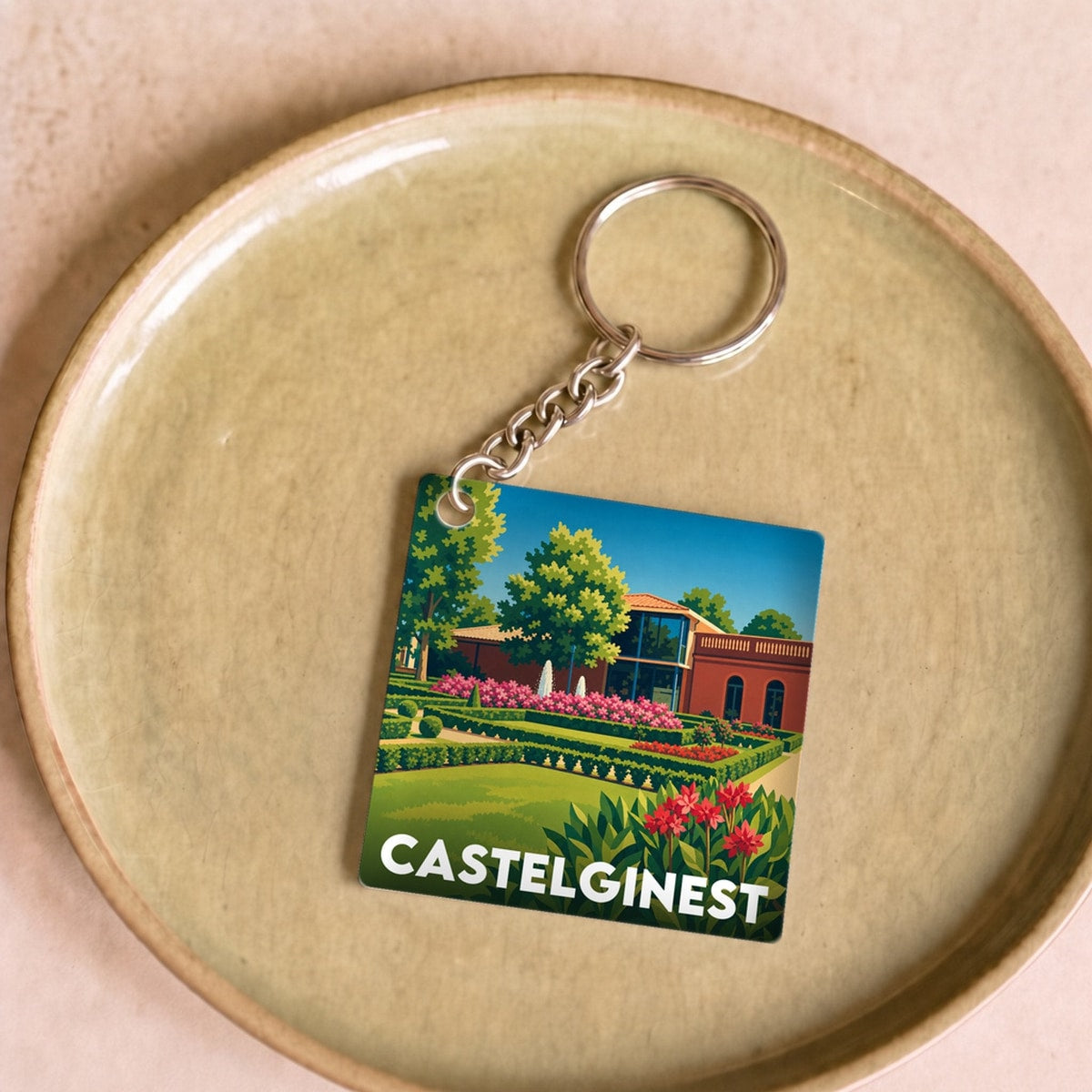 Porte-clés souvenir de la ville de Castelginest avec une illustration stylisée de ses jardins.