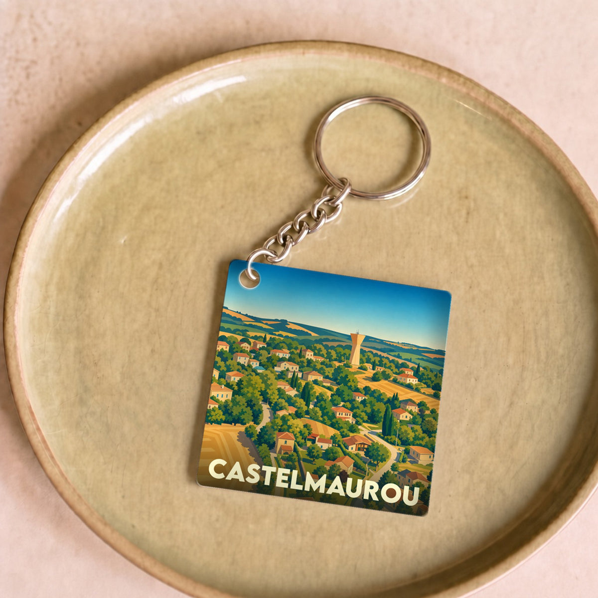Porte-clés souvenir de la ville de Castelmaurou avec une illustration stylisée de ses paysages.