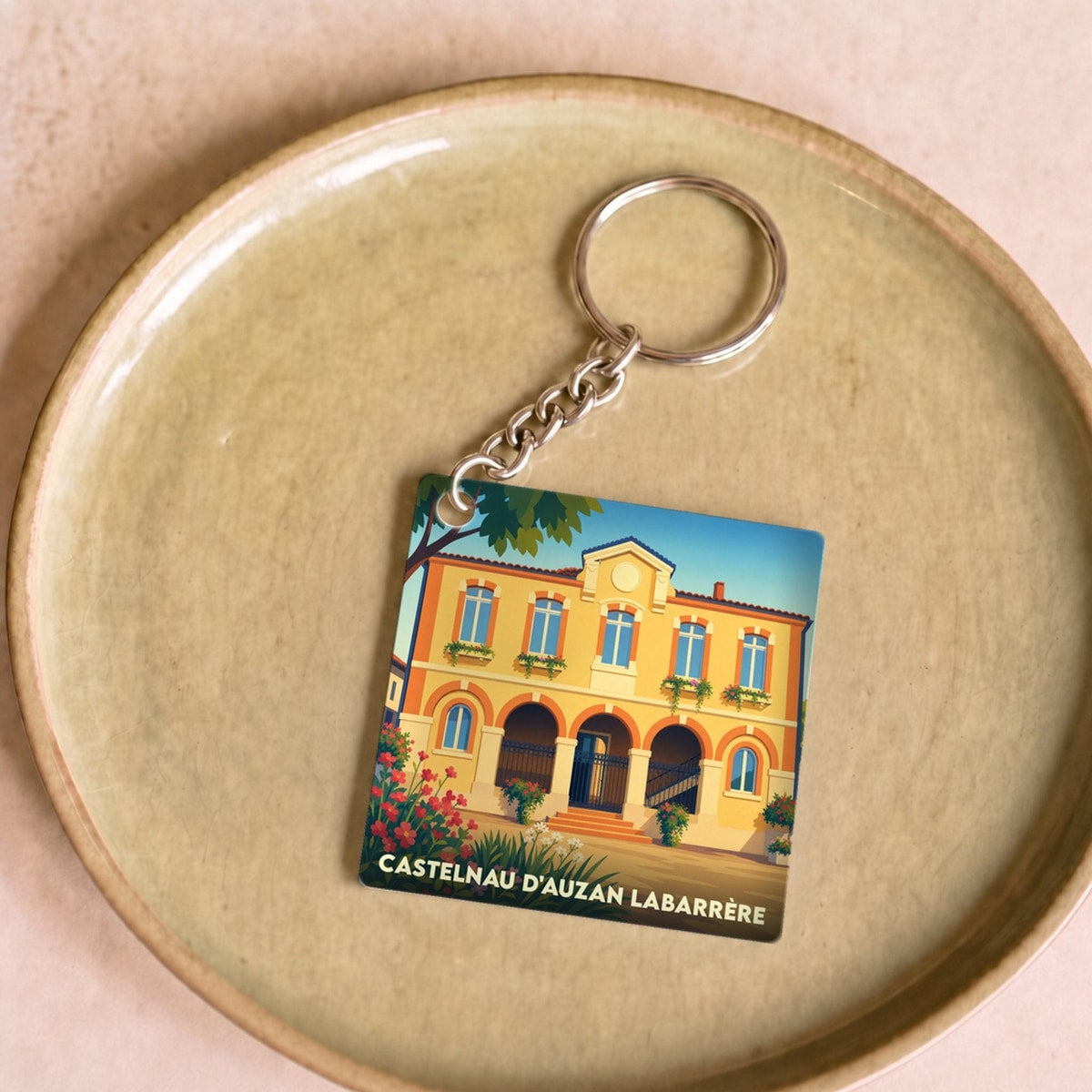 Porte-clés souvenir de la commune de Castelnau d'Auzan Labarrère avec une illustration stylisée.