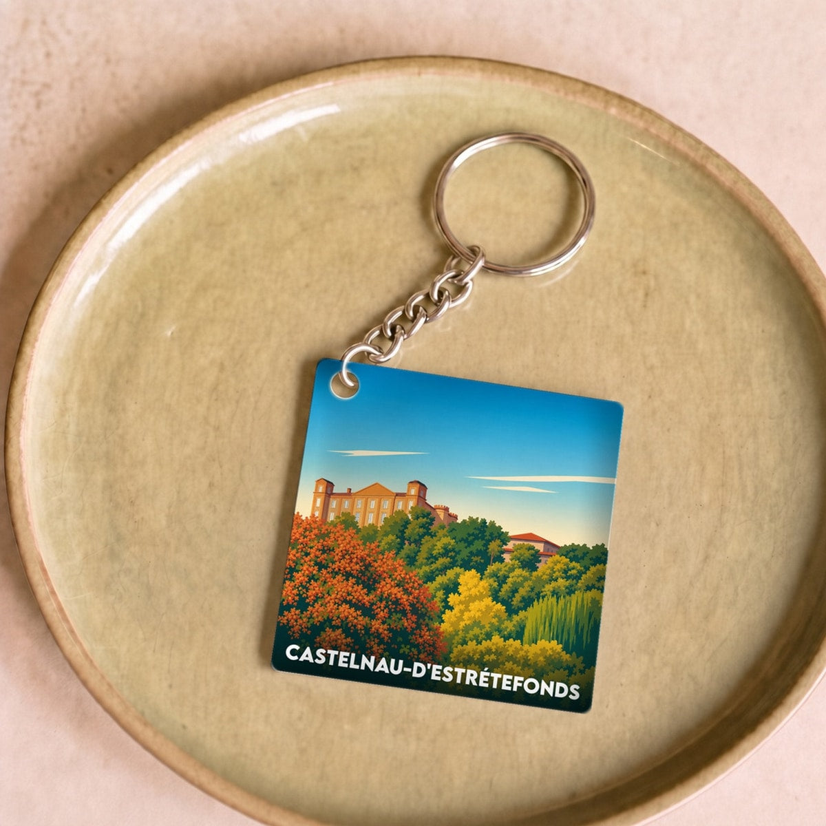 Porte-clés souvenir de la ville de Castelnau-d'Estrétefonds avec une illustration stylisée.