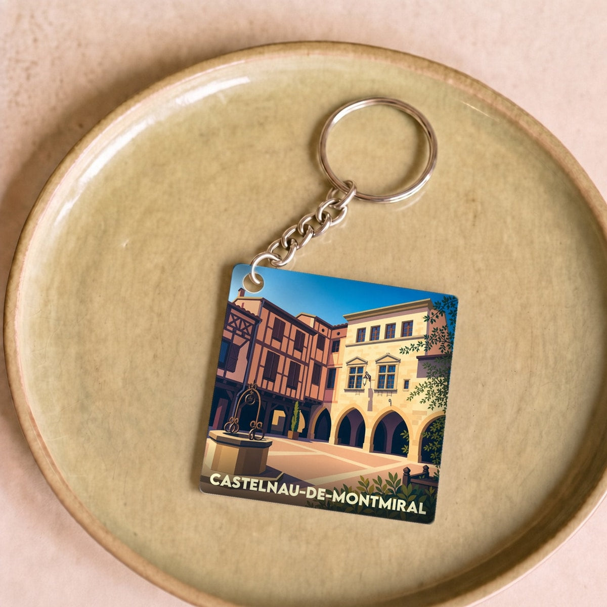 Porte-clés souvenir de la ville de Castelnau-de-Montmiral avec une illustration stylisée de sa place centrale.
