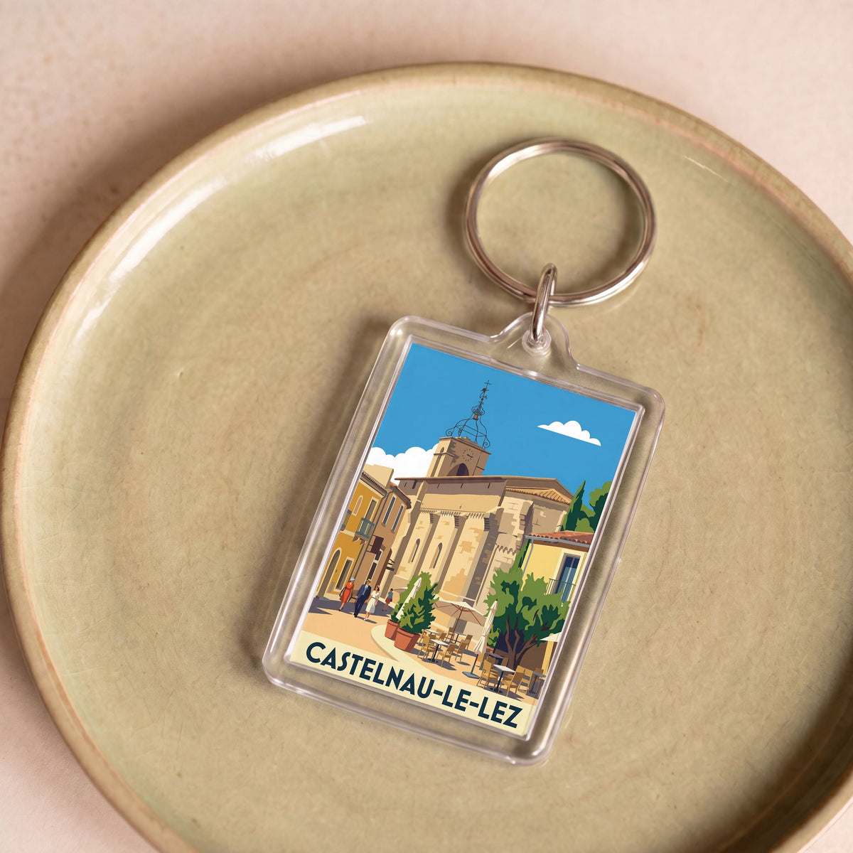 Porte-clés souvenir de la ville de Castelnau-le-Lez avec une illustration stylisée.