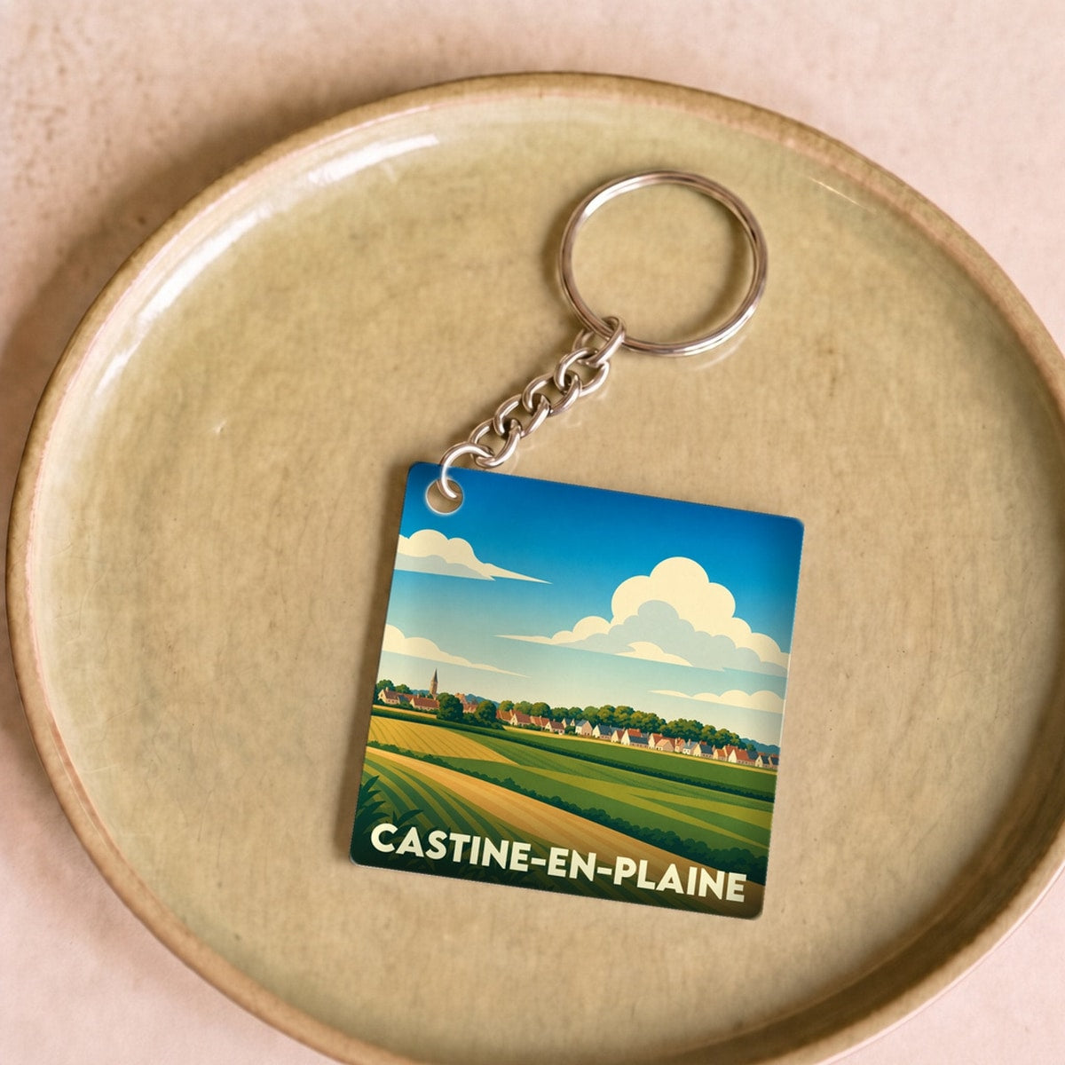 Porte-clés souvenir de la ville de Castine-en-Plaine avec une illustration stylisée de paysages ruraux.