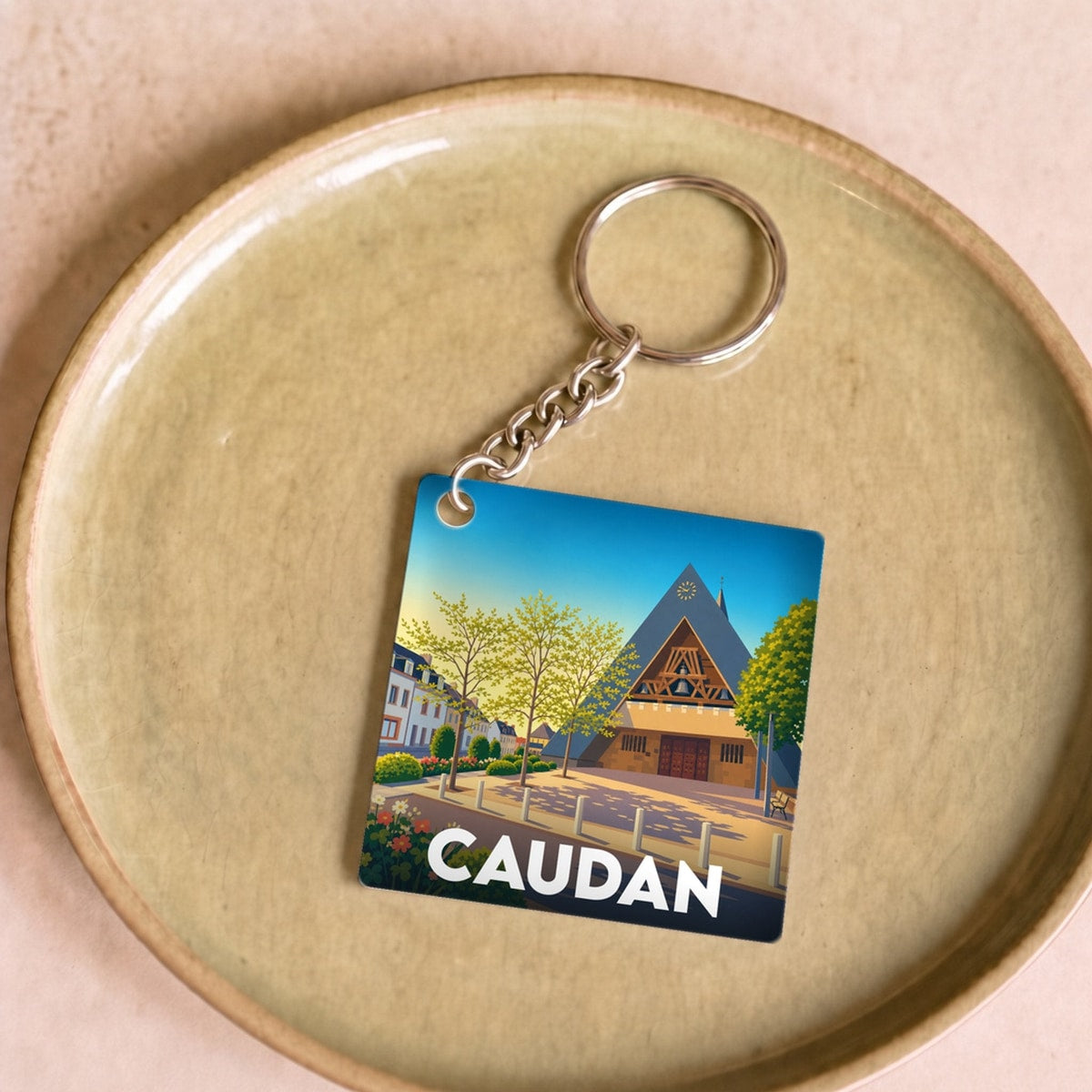 Porte-clés souvenir de la ville de Caudan avec une illustration stylisée.