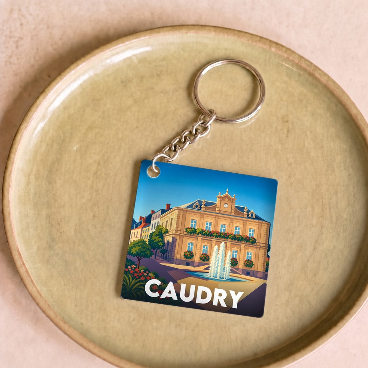 Porte-clés souvenir de la ville de Caudry avec une illustration stylisée.