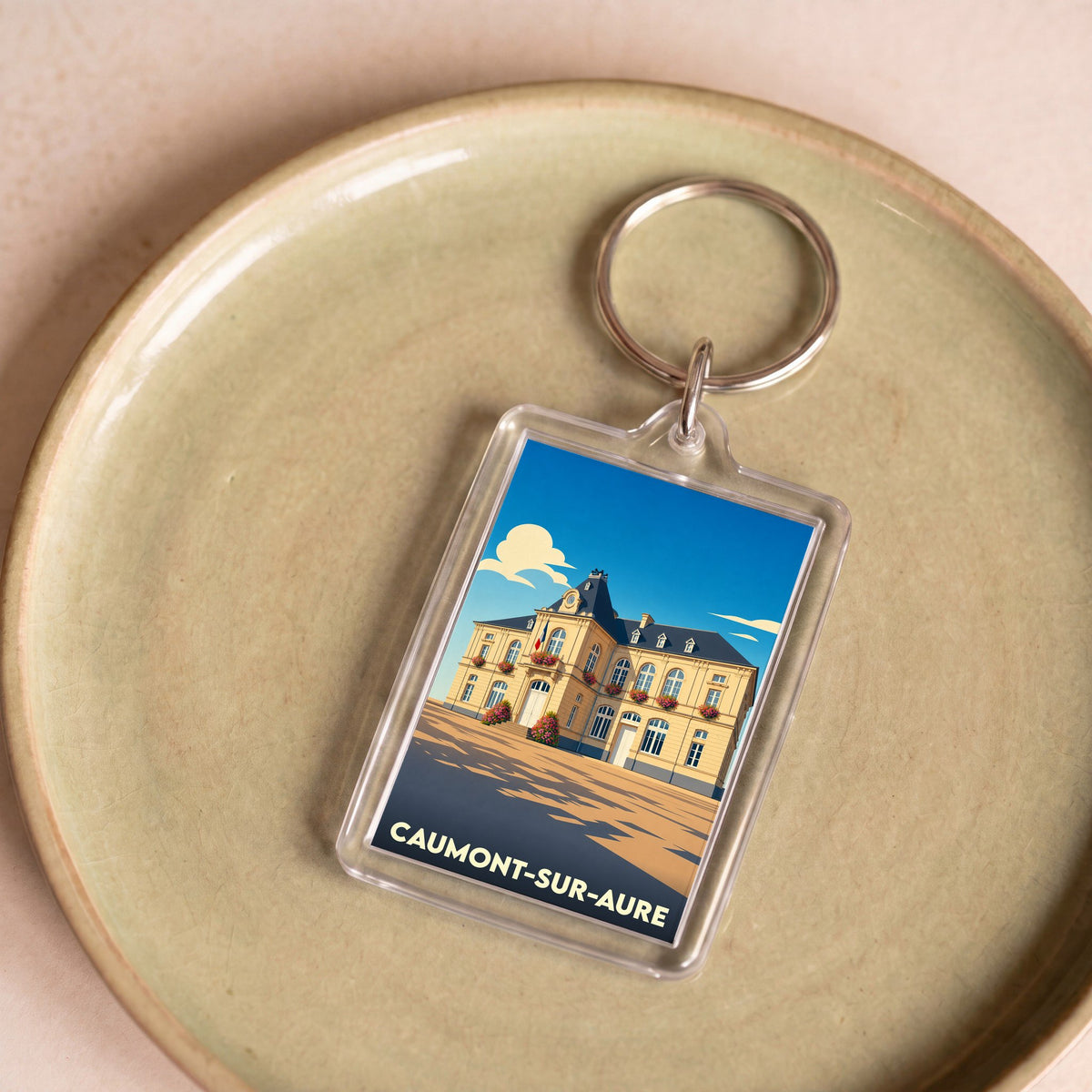 Porte-clés souvenir de la ville de Caumont-sur-Aure avec une illustration stylisée de la mairie.
