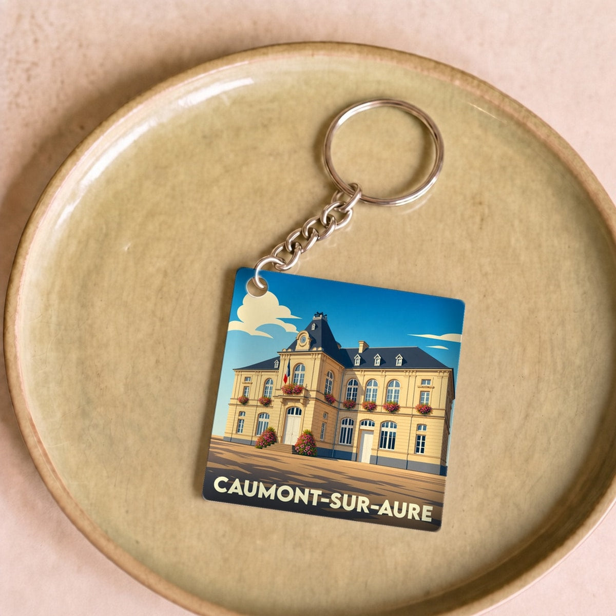 Porte-clés souvenir de la ville de Caumont-sur-Aure avec une illustration stylisée de la mairie.