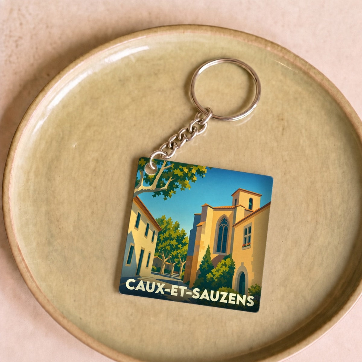 Porte-clés souvenir de la ville de Caux-et-Sauzens avec une illustration stylisée.