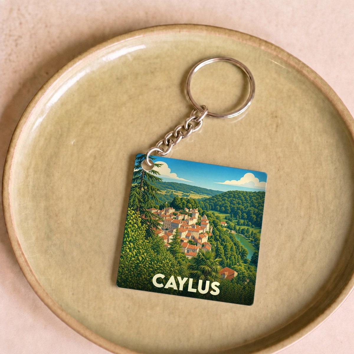 Porte-clés souvenir de la ville de Caylus avec une illustration stylisée et colorée du village.