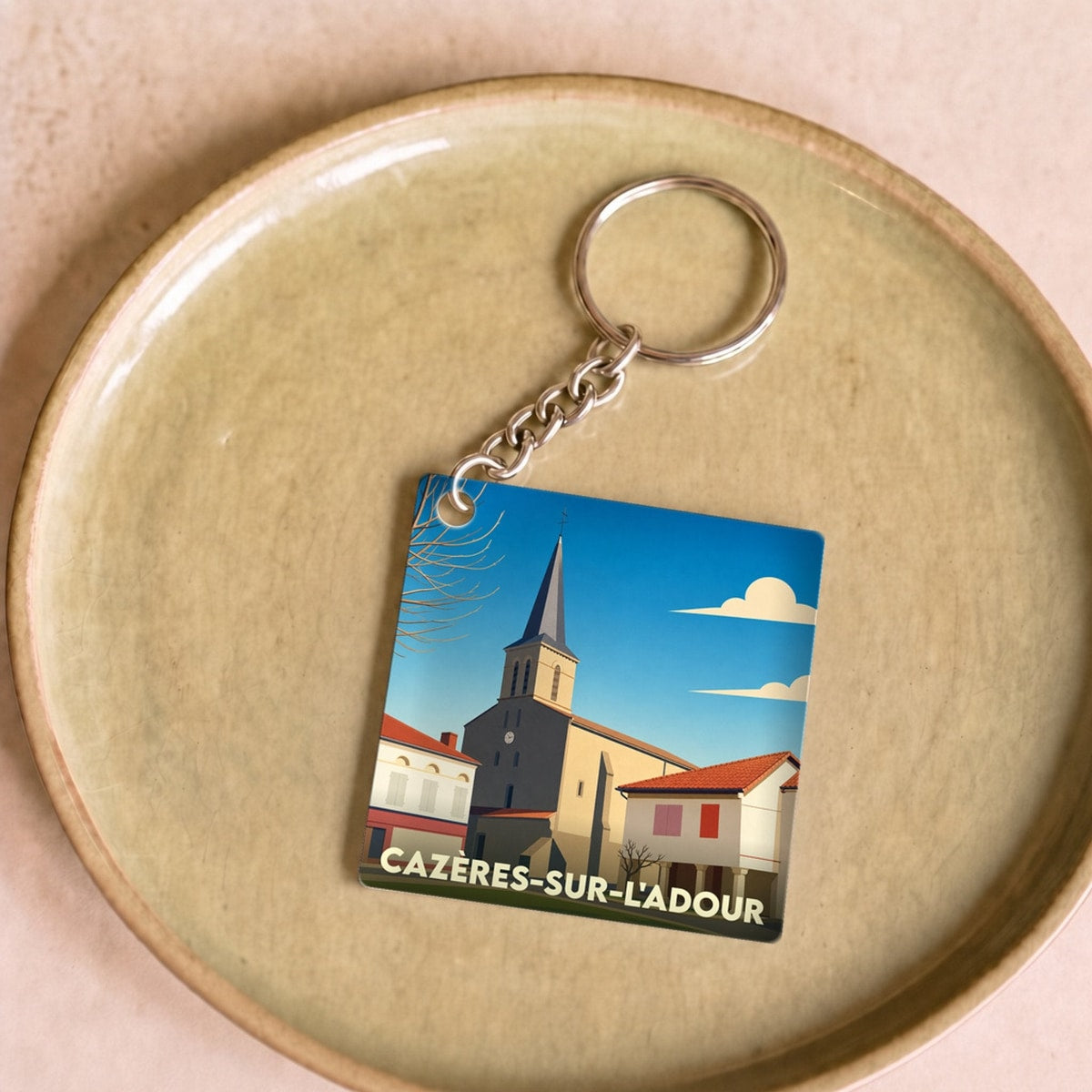 Porte-clés souvenir de la ville de Cazères-sur-l'Adour avec une illustration stylisée de son église.