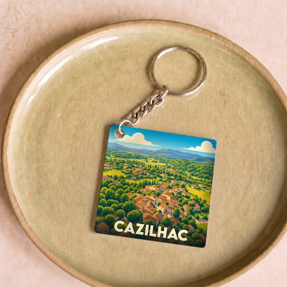 Porte-clés souvenir de la ville de Cazilhac avec une illustration stylisée de son paysage urbain et verdoyant.