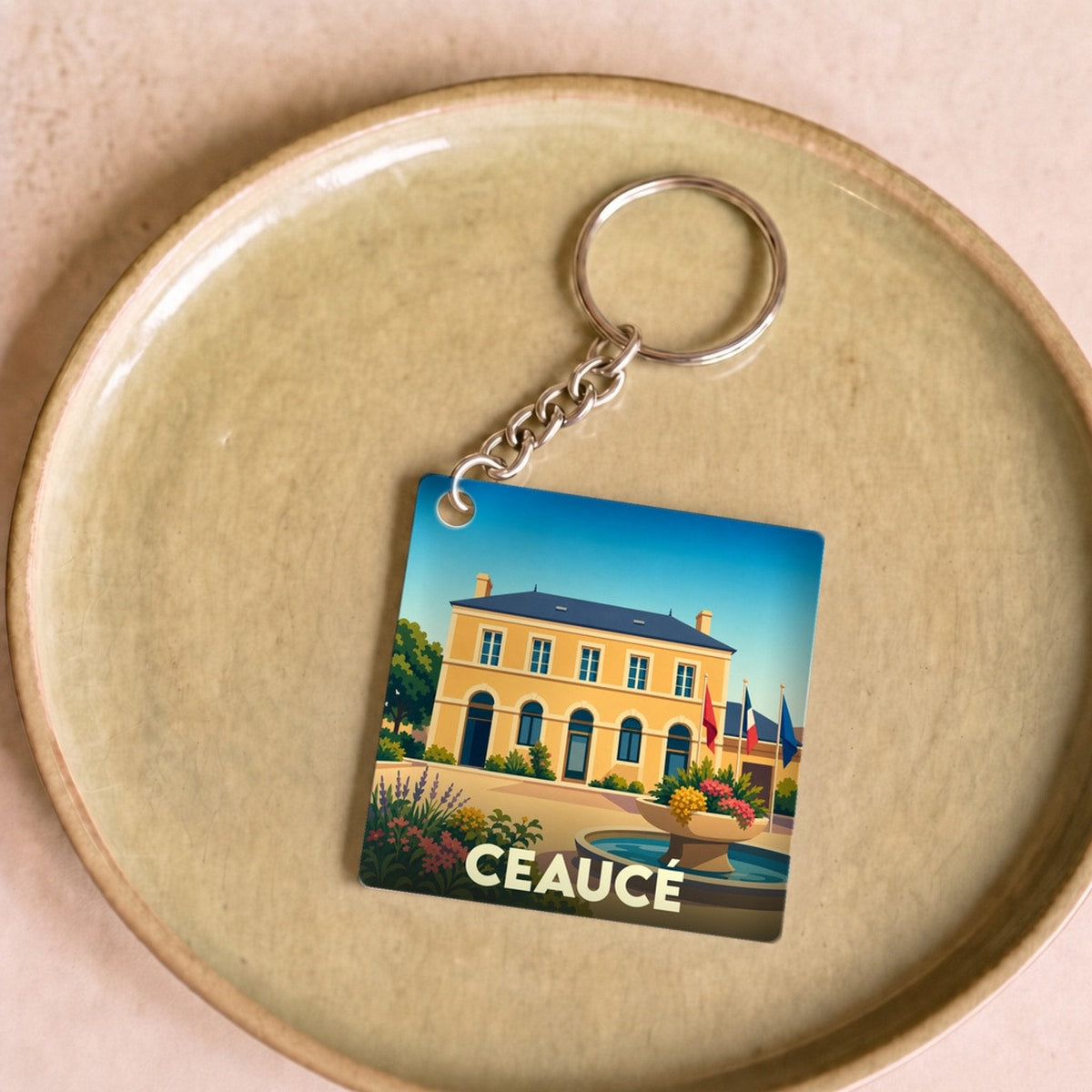 Porte-clés souvenir de la ville de Ceaucé avec une illustration stylisée de la mairie.
