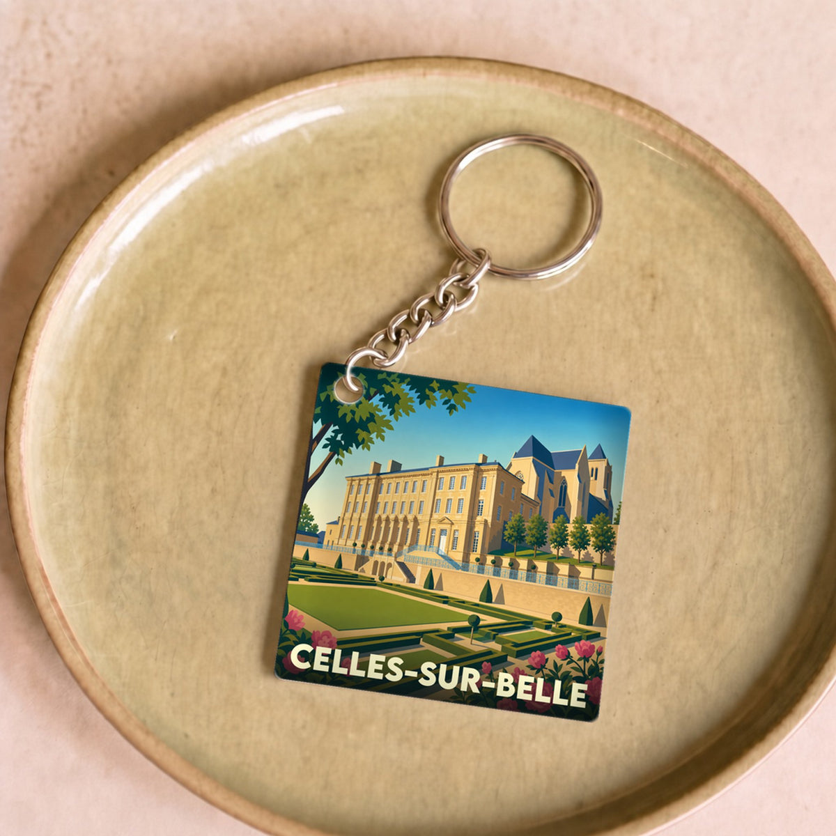 Porte-clés souvenir de la ville de Celles-sur-Belle avec une illustration stylisée de son abbaye et de ses jardins.