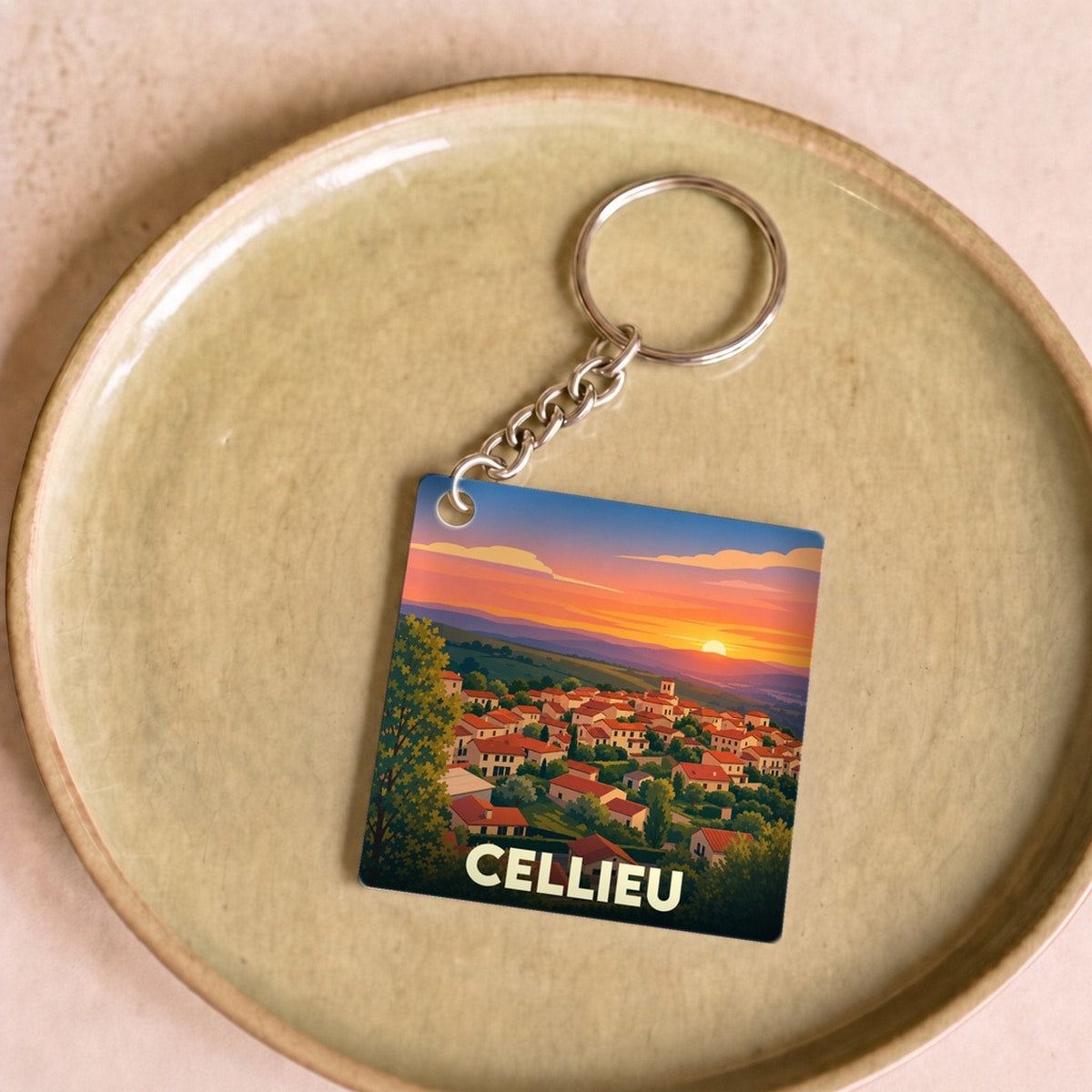 Porte-clés souvenir de la ville de Cellieu avec une illustration stylisée d'un coucher de soleil sur le village.