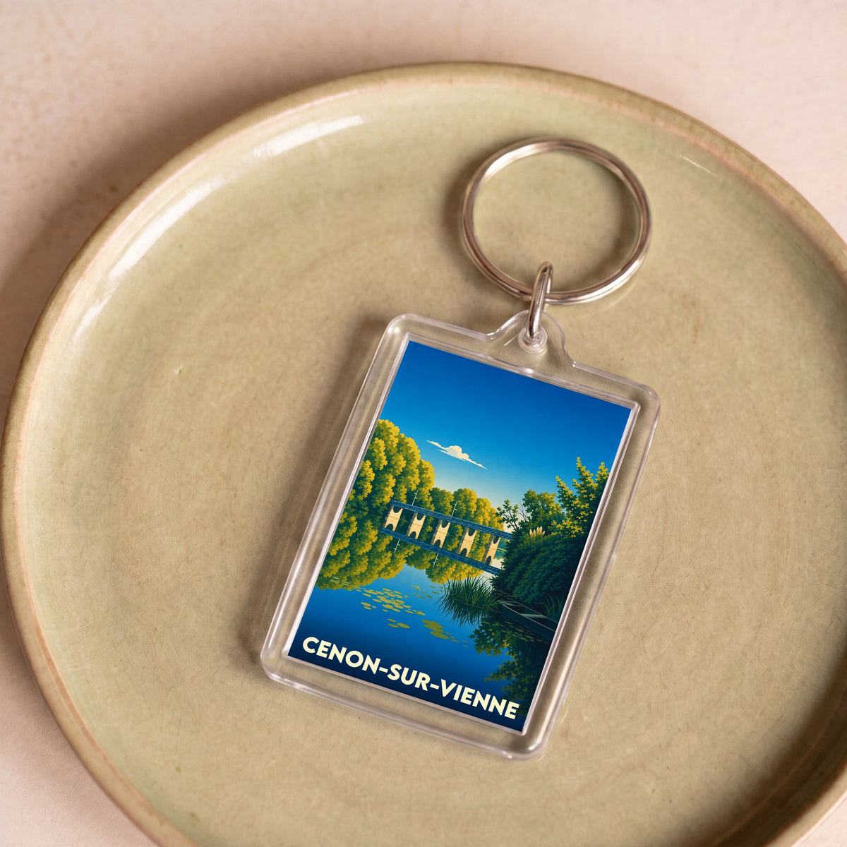 Porte-clés souvenir de la ville de Cenon-sur-Vienne avec une illustration stylisée d'un pont au-dessus de l'eau.