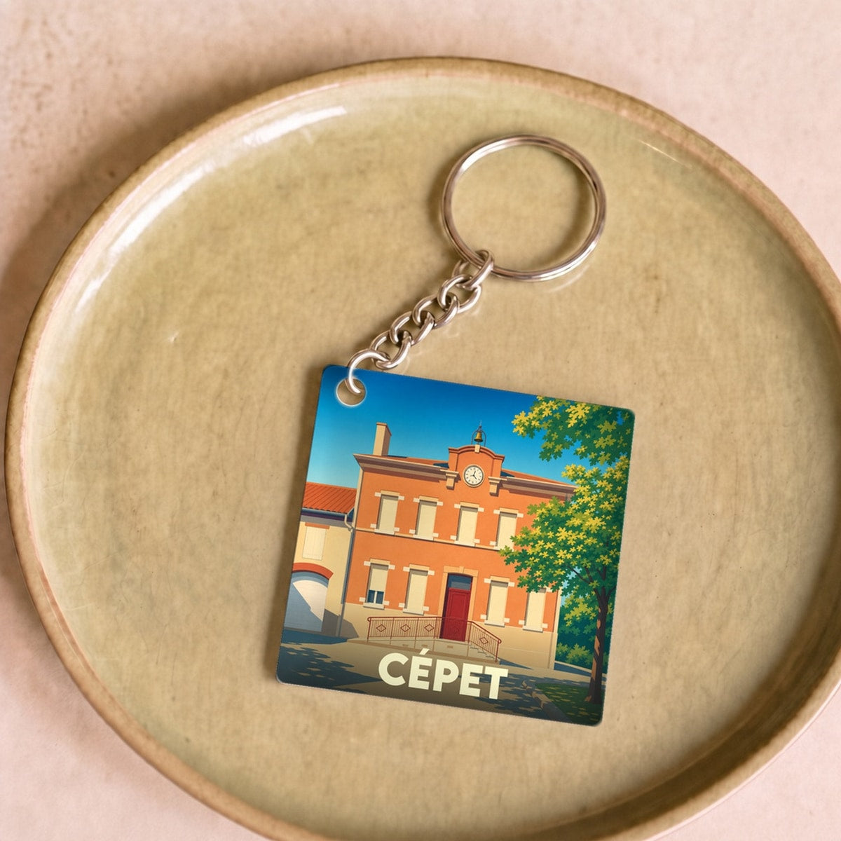 Porte-clés souvenir de la ville de Cépet avec une illustration stylisée de sa mairie.
