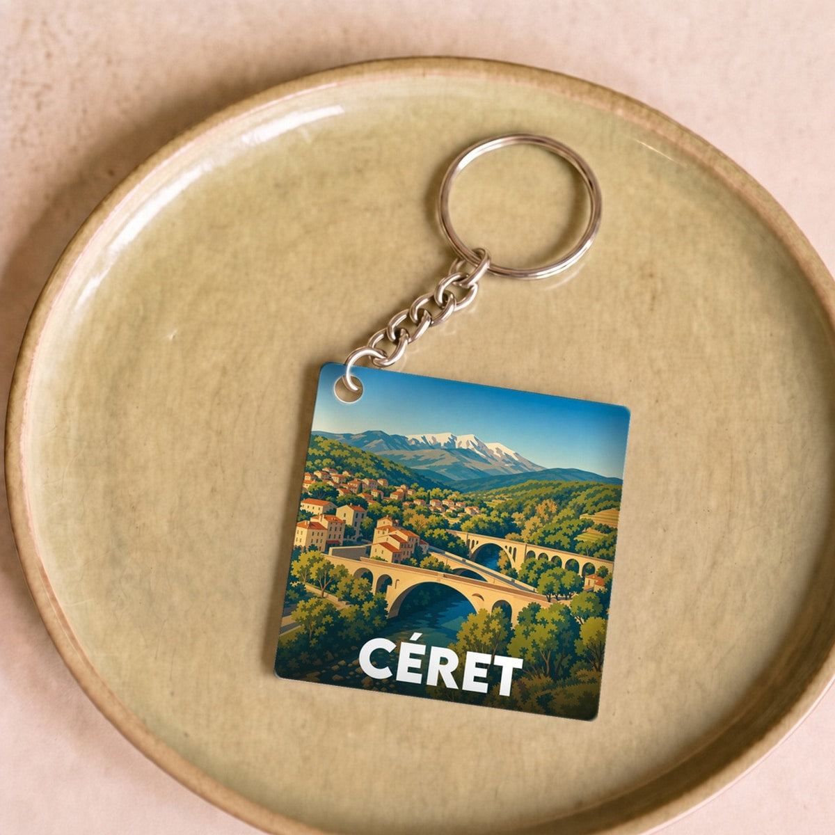 Porte-clés souvenir de la ville de Céret avec une illustration stylisée de son pont et des montagnes.