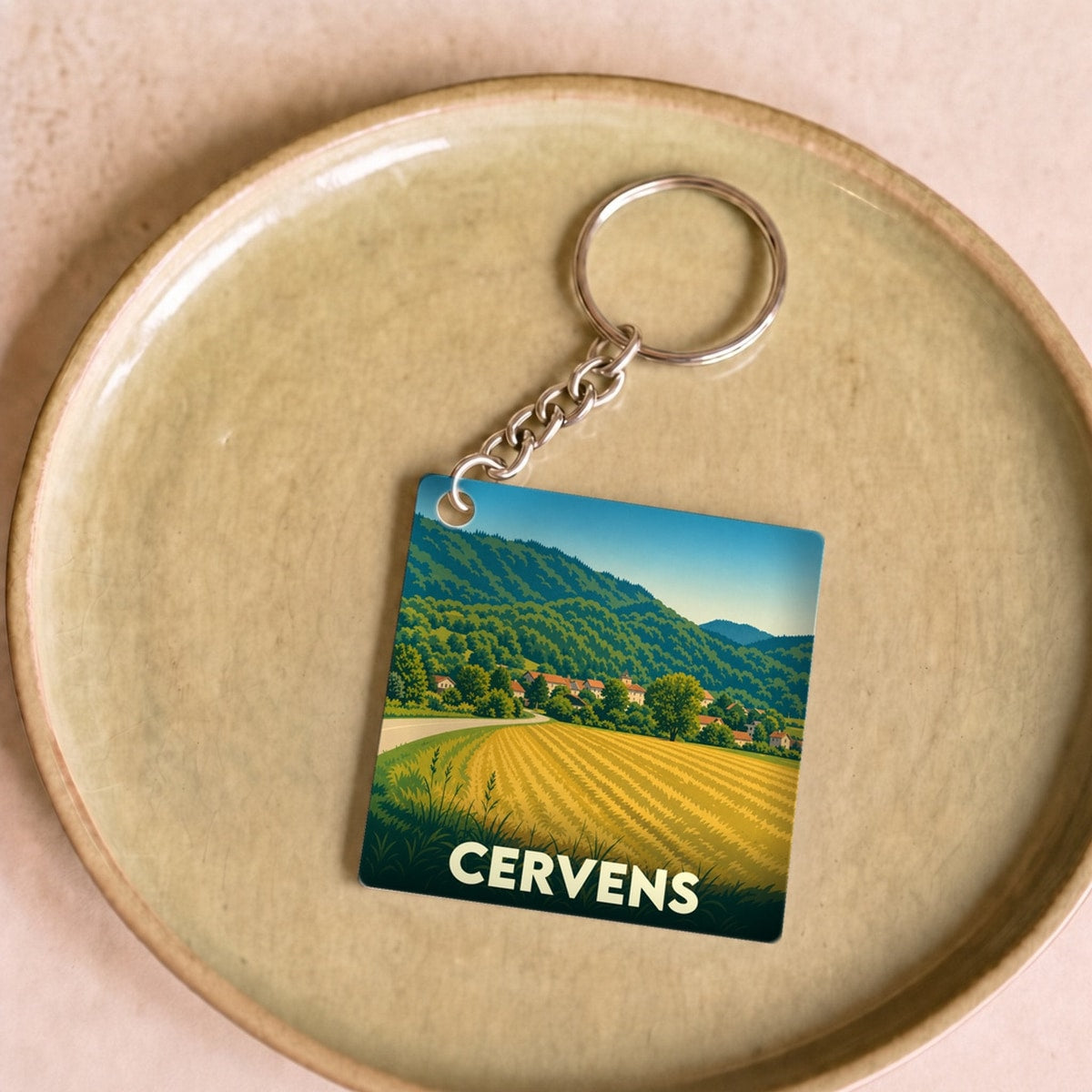 Porte-clés souvenir de la ville de Cervens avec une illustration de paysage vallonné.