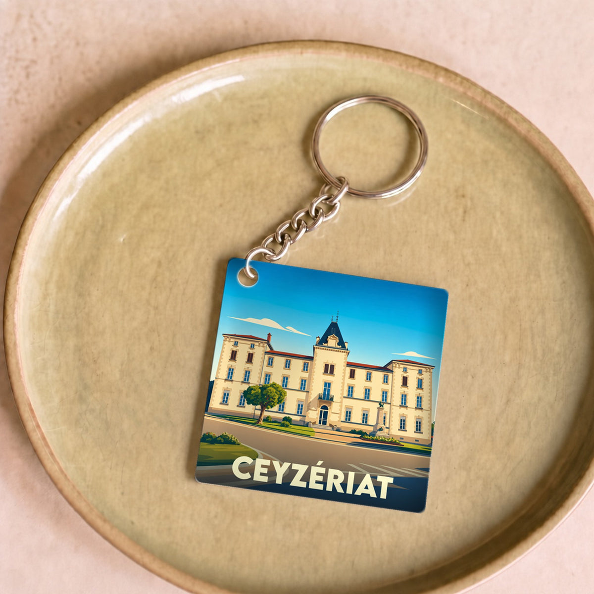 Porte-clés souvenir de la ville de Ceyzériat avec une illustration stylisée d'un bâtiment historique.